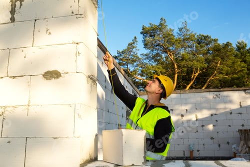 Preview: Construction worker at construction site measures the length of the window opening