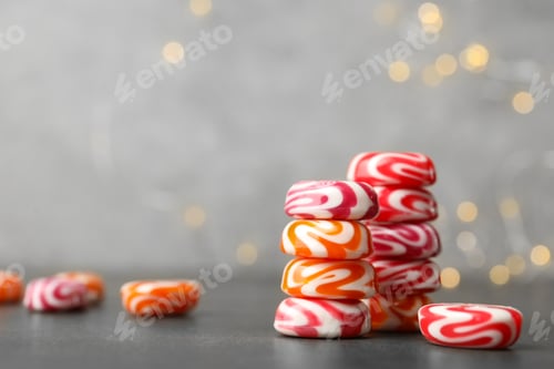Preview: Stacked tasty hard candies on grey table. Space for text