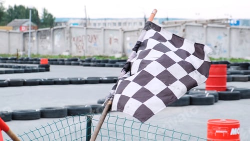 Preview: Close-up view of red and checkered start and finish flags on the outdoor karting track. Media. Kart