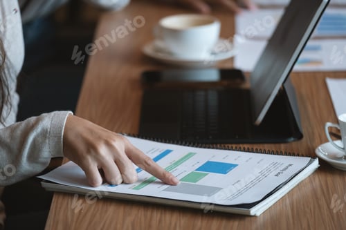 Preview: Businesswoman holding pens and holding graph paper are meeting to plan sale for monthly target