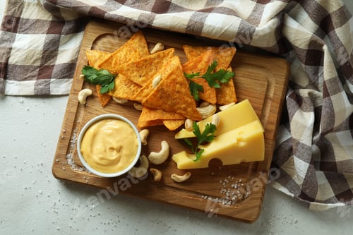 Preview: Board with cheese sauce and snacks on white textured table