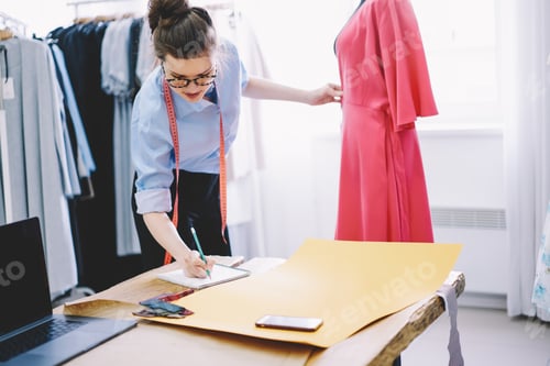 Preview: Woman dressmaker taking measurements while working