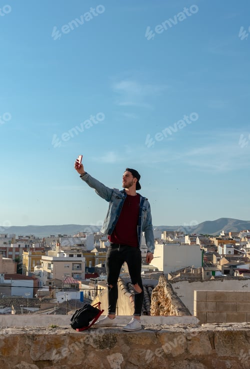 Preview: Young man takes a picture with the city in the background