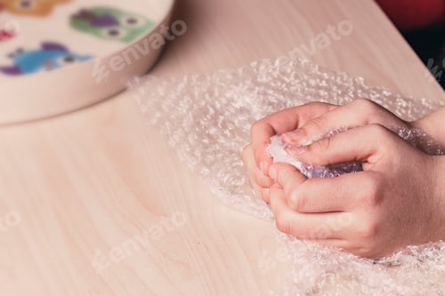 Preview: Stress concept. Woman's hands popping bubbles from a bubble paper.