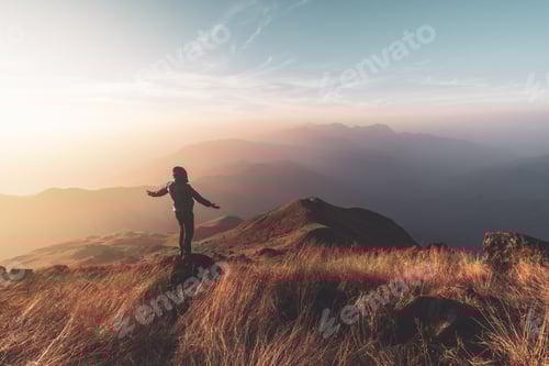Preview: Young man traveler looking beautiful landscape at sunset on mountain