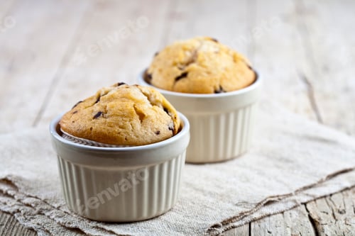 Preview: Homemade fresh muffins on ceramic white bowls on linen napkin.