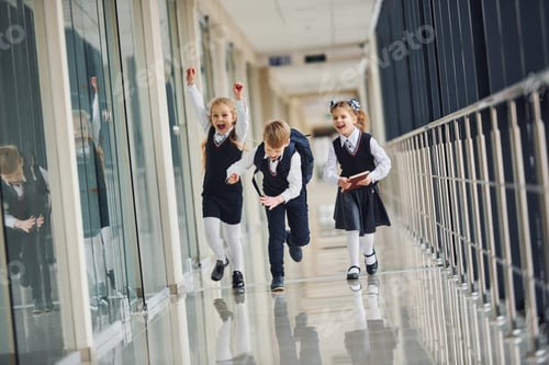 Preview: Active school kids in uniform running together in corridor. Conception of education