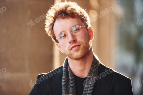 Preview: Portrait of elegant young man in glasses and formal classy clothes outdoors in the city
