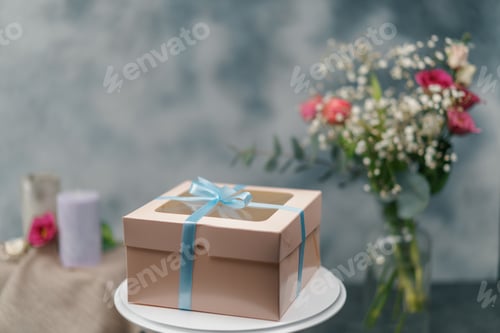 Preview: a packed delicious cake in a gift box with a bow stands on stand on a background of flowers