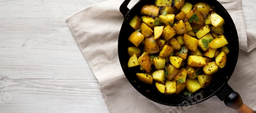 Preview: Homemade Roasted Potatoes with Mustard Seeds in a cast-iron pan, top view. Flat lay, overhead
