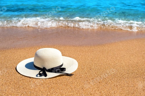 Preview: White woman straw hat laying on tropical sand beach with blue vibrant ocean water in background on