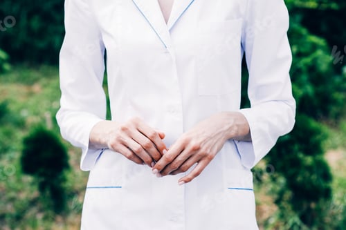 Preview: cropped view of doctor in white coat standing in park