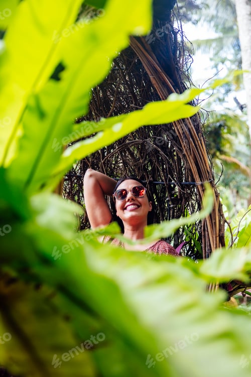 Preview: A female tourist is sitting on a large bird nest on a tree at Bali island