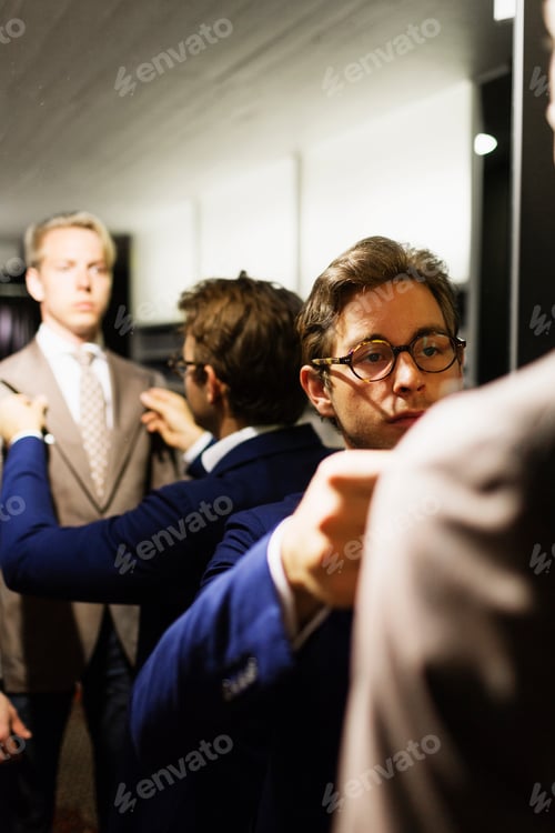 Preview: Salesman adjusting customer's suit in fitting room at clothing store