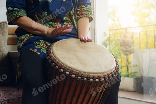 Preview: Female hands of an unrecognizable woman playing the Djembe drum in home