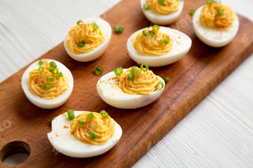 Preview: Homemade Deviled Eggs with Chives on a rustic wooden board on a white wooden background