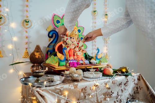 Preview: Close up Indian man putting flower garland engages in worship at home altar for god Ganesh