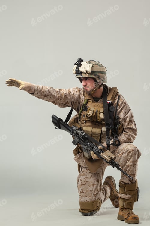 Preview: Soldier in camouflage gear kneels and gestures with weapon in controlled setting