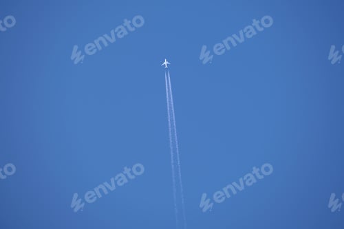 Preview: Distant passenger jet plane flying on high altitude on clear blue sky leaving white smoke trace of