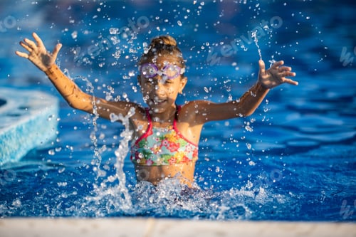 Preview: A girl with swimming goggles jumps into a pool with clear water on the background