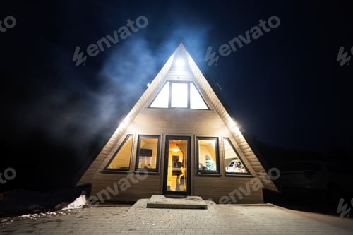 Preview: Triangle country house at night with smoke from bonfire.