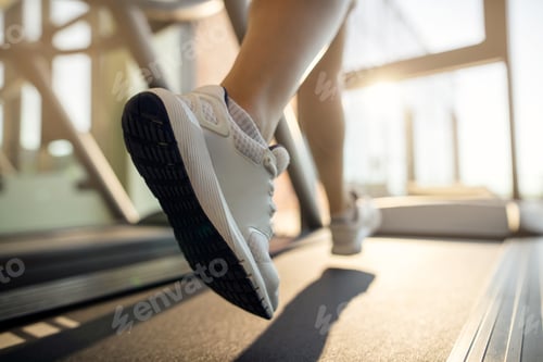 Preview: Close-up of sportswoman jogging on running track at health club.