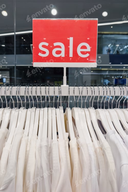 Preview: Rack of White Clothes with a Red Sign that Says Sale Hanging from it
