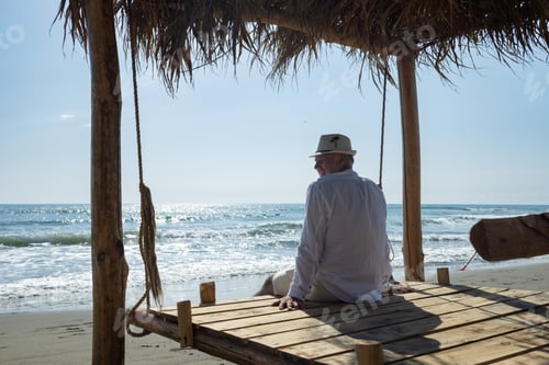 Preview: A tourist rests on a swing bed with a thatched roof and looks at the blue sea. Montenegro