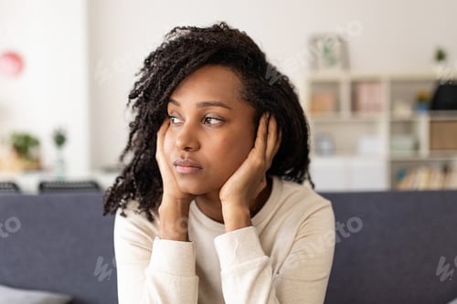 Preview: Thoughtful woman feeling sad sitting on sofa at home