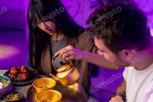 Preview: a girl pours the traditional Korean low-alcohol drink makoli from a golden teapot into cup with ice