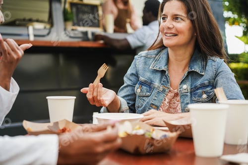 Preview: 50's woman eating at food truck restaurant outdoor - Spring lifestyle and dinner concept