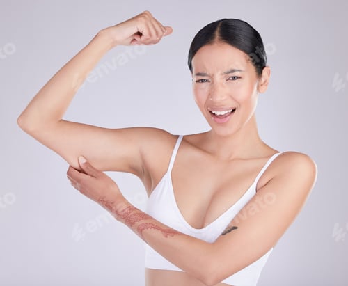 Preview: Shot of an attractive young woman standing and tugging at excess skin on her arm