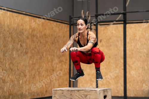 Preview: Strong sportive woman jumping into box in a gym