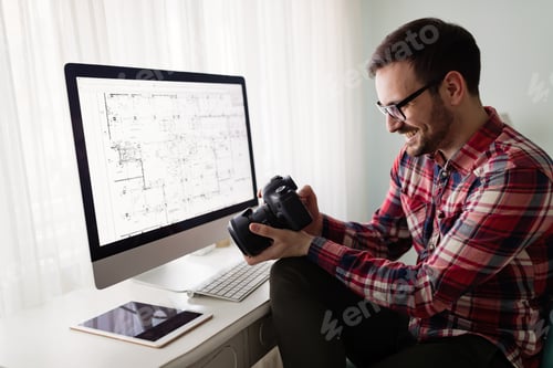 Vista previa: Joven diseñador guapo trabajando en un proyecto en la computadora