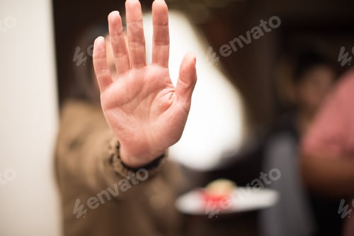 Preview: Woman holding her hand up to conceal herself
