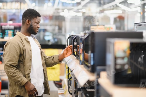 Preview: An African-American man is choosing a new microwave oven at an electronics store
