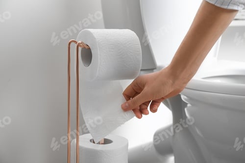 Preview: Woman taking toilet paper from roll holder in bathroom, closeup