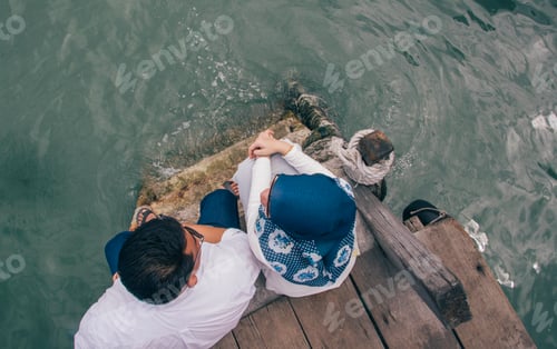 Man and Woman Sitting by Calm Ocean Water