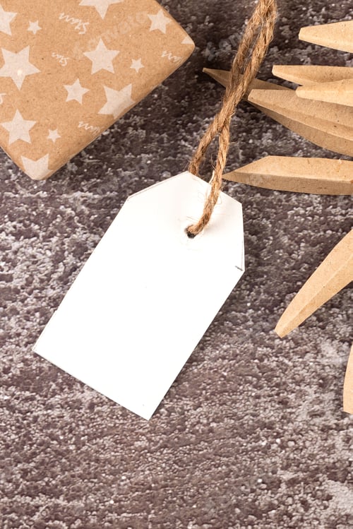 Preview: Empty white tag with gifts and Christmas decor on dark conkrete background.