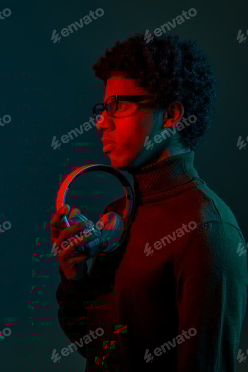 Preview: Side view on man holding headphones over dark