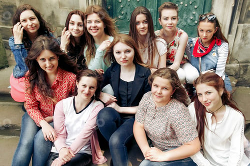Preview: young happy women sitting on stairs posing