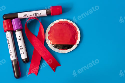 Preview: AIDS ribbon with blood tubes from sexually transmitted disease tests and condom on blue background