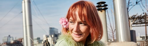 Preview: banner of happy attractive woman with flower in hair looking away on roof terrace in Vienna, Austria