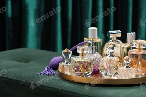 Preview: Different luxury perfumes on green pouf near teal curtains, closeup. Space for text