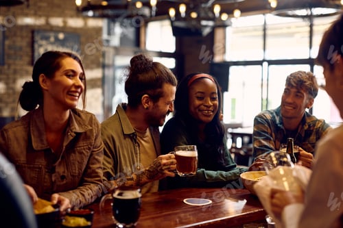 Preview: Multiracial group of happy friends drinking beer at bar counter.