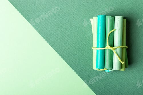 Preview: A few pastel crayons tied with a ribbon on green pastel paper. Green palette