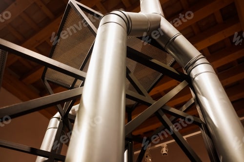 Preview: Vertical metal pipes inside an industrial warehouse.