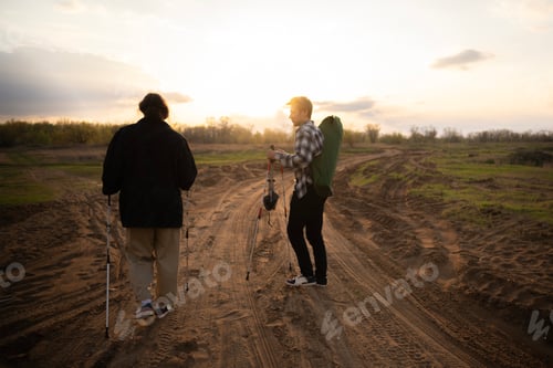 Visualização: Amigos caminham juntos por um caminho arenoso, curtindo a natureza e o brilho quente do pôr do sol em seu advento