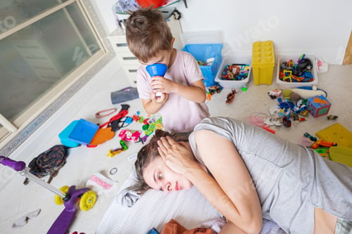 Preview: Young mother with little boy in nursery room with mess around in postnatal depression