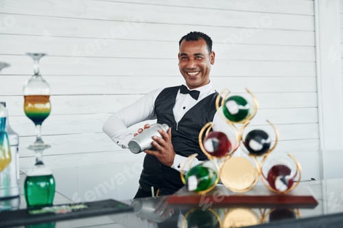 Preview: At the bar. Black waiter in formal clothes is at his work outdoors at sunny daytime